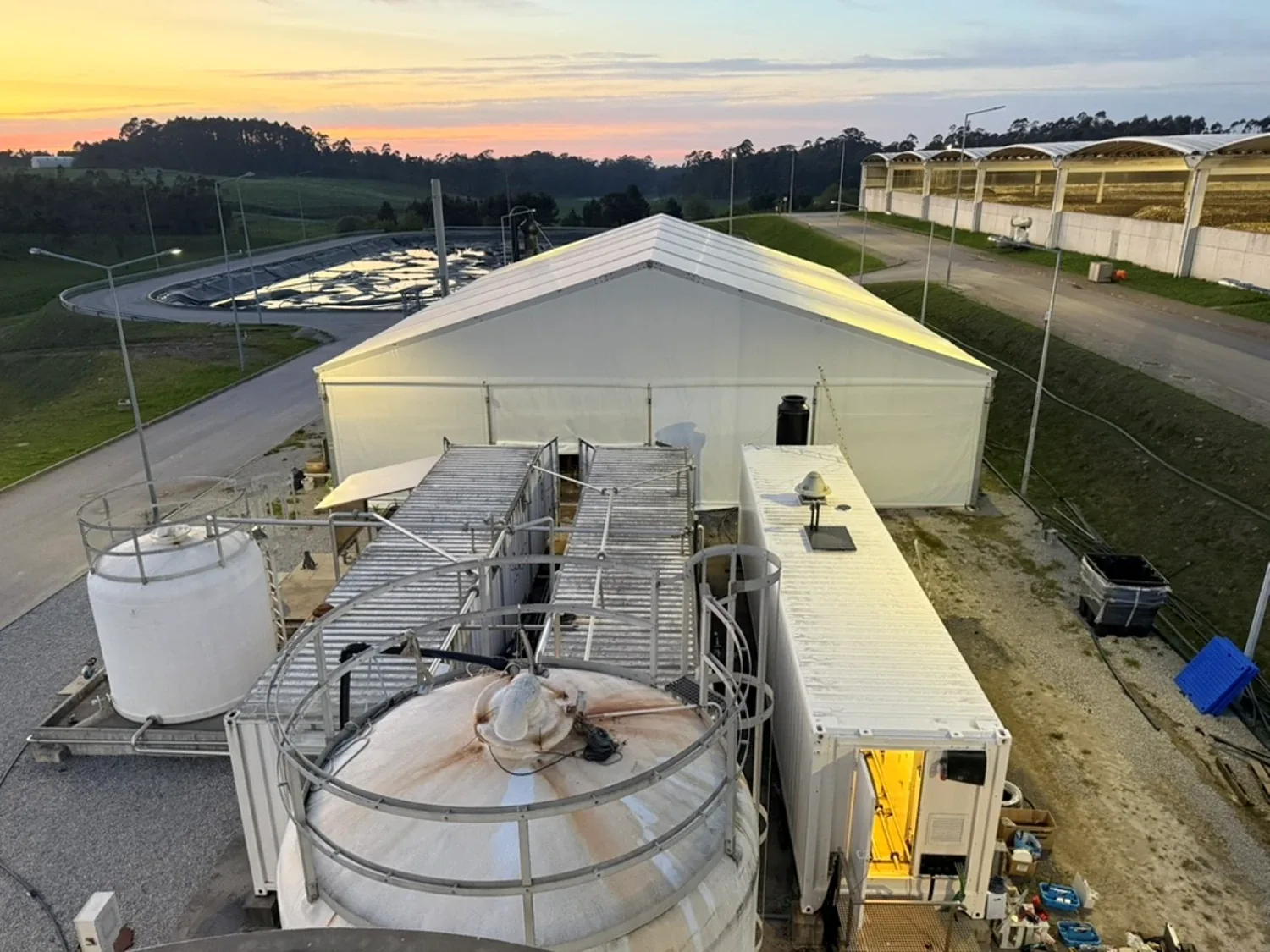 Landfill leachate plant with tent hall, containers and leachate pond at sunset in Portugal