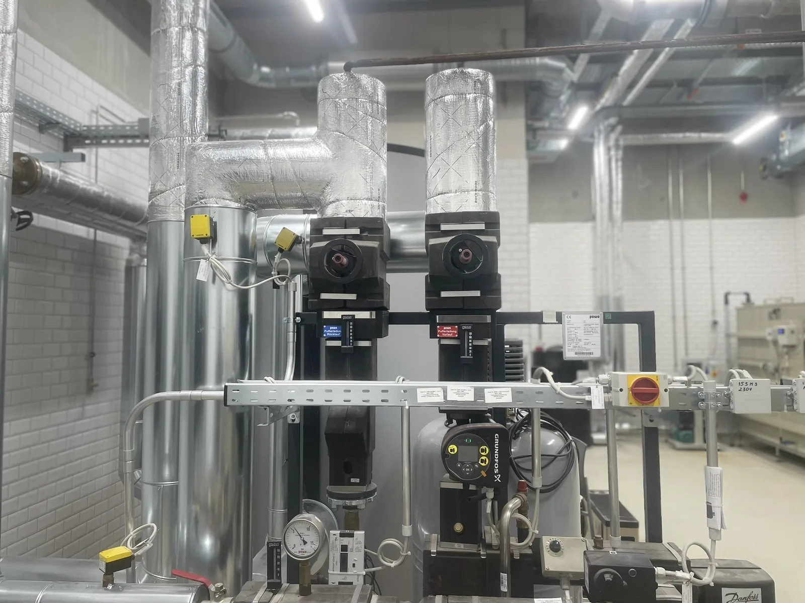 Insulated lines with control valves and pumps in the plant room at Frankfurt Airport