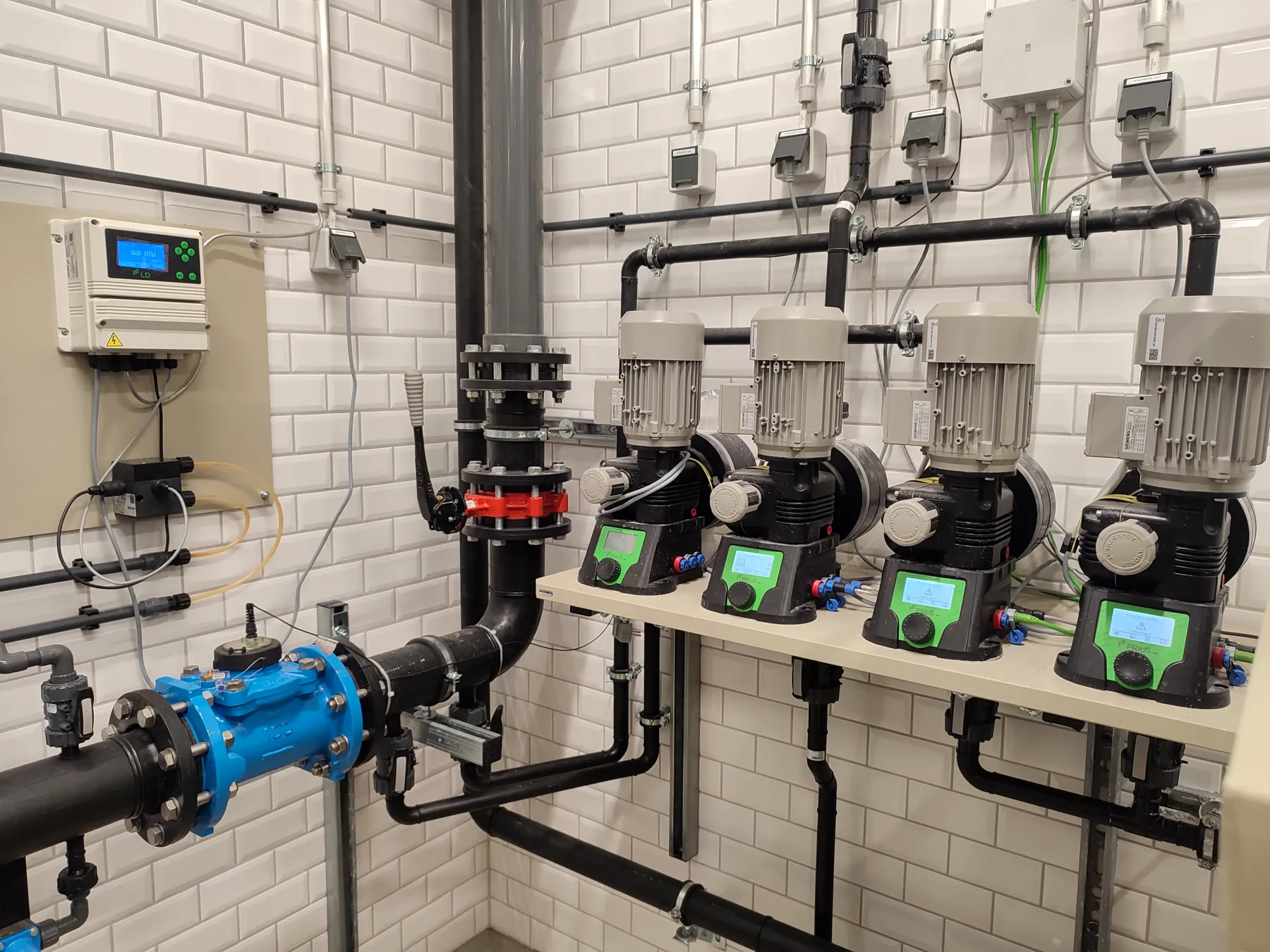 Row of four dosing pumps mounted above the drinking-water main