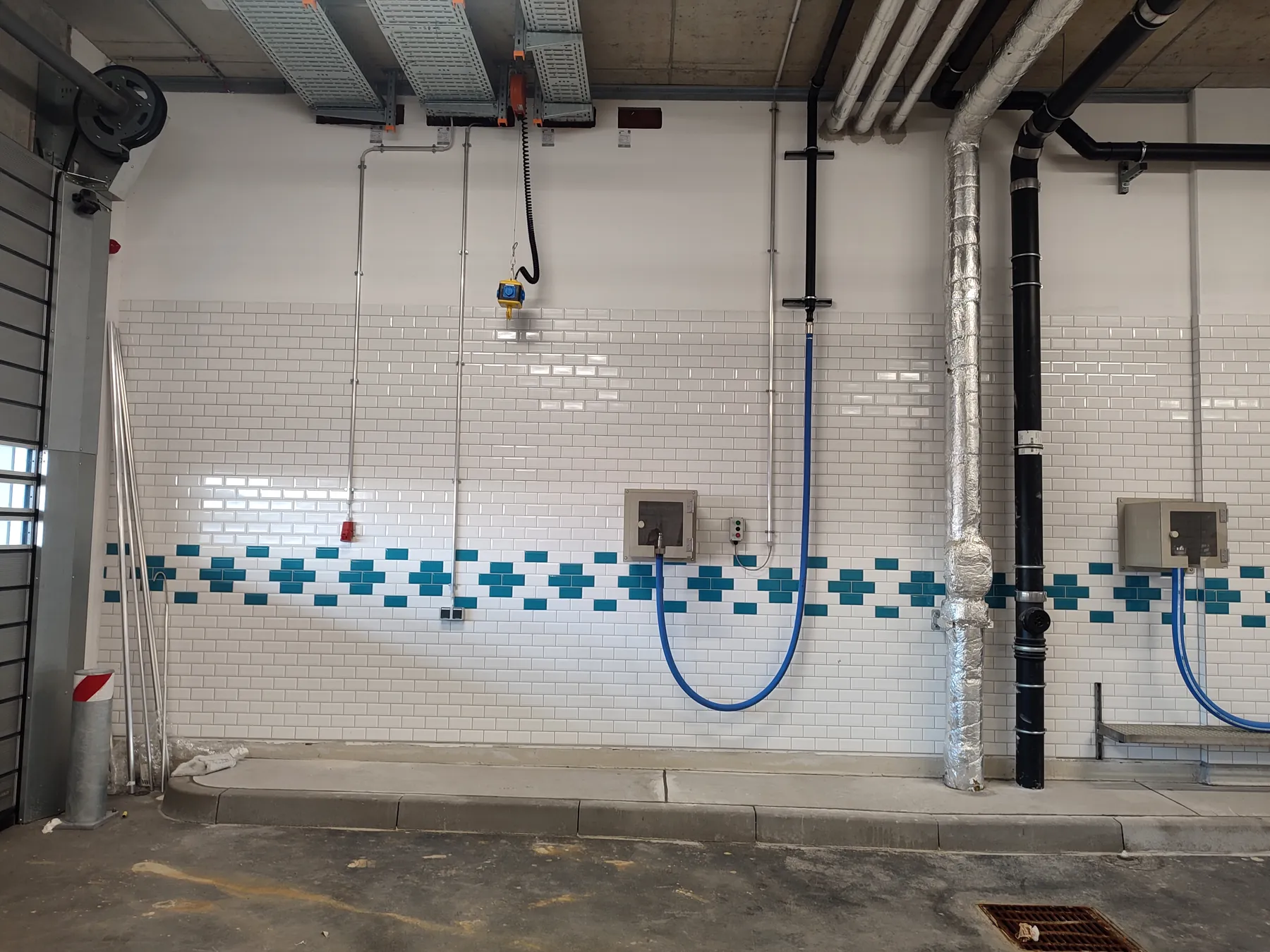 Tiled filling bay with wall-mounted hose connections